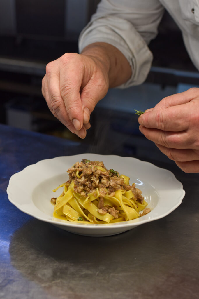 Chef che completa un piatto di tagliatelle